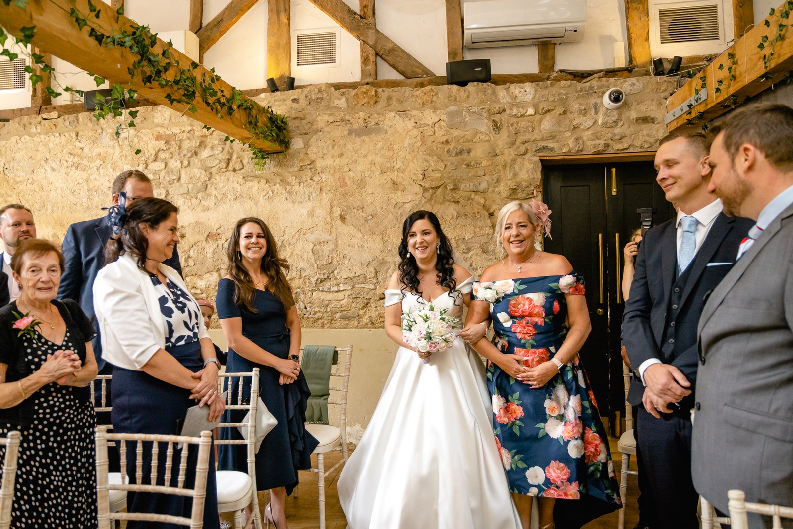 The bride at the ceremony front, her mother in a floral dress beside her