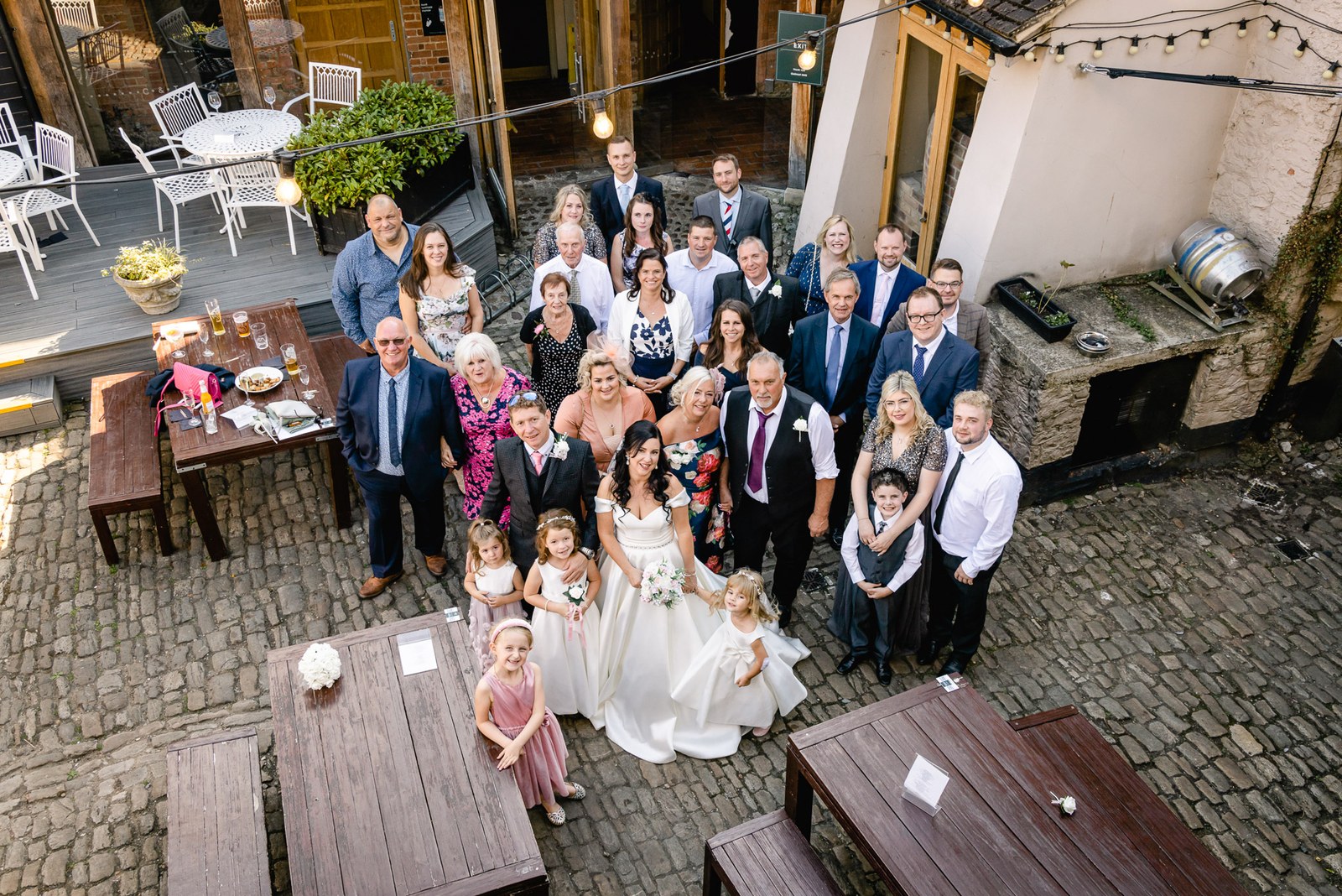 Guests gather with the couple for a group photo in the cobbled courtyard of the Crown & Thistle