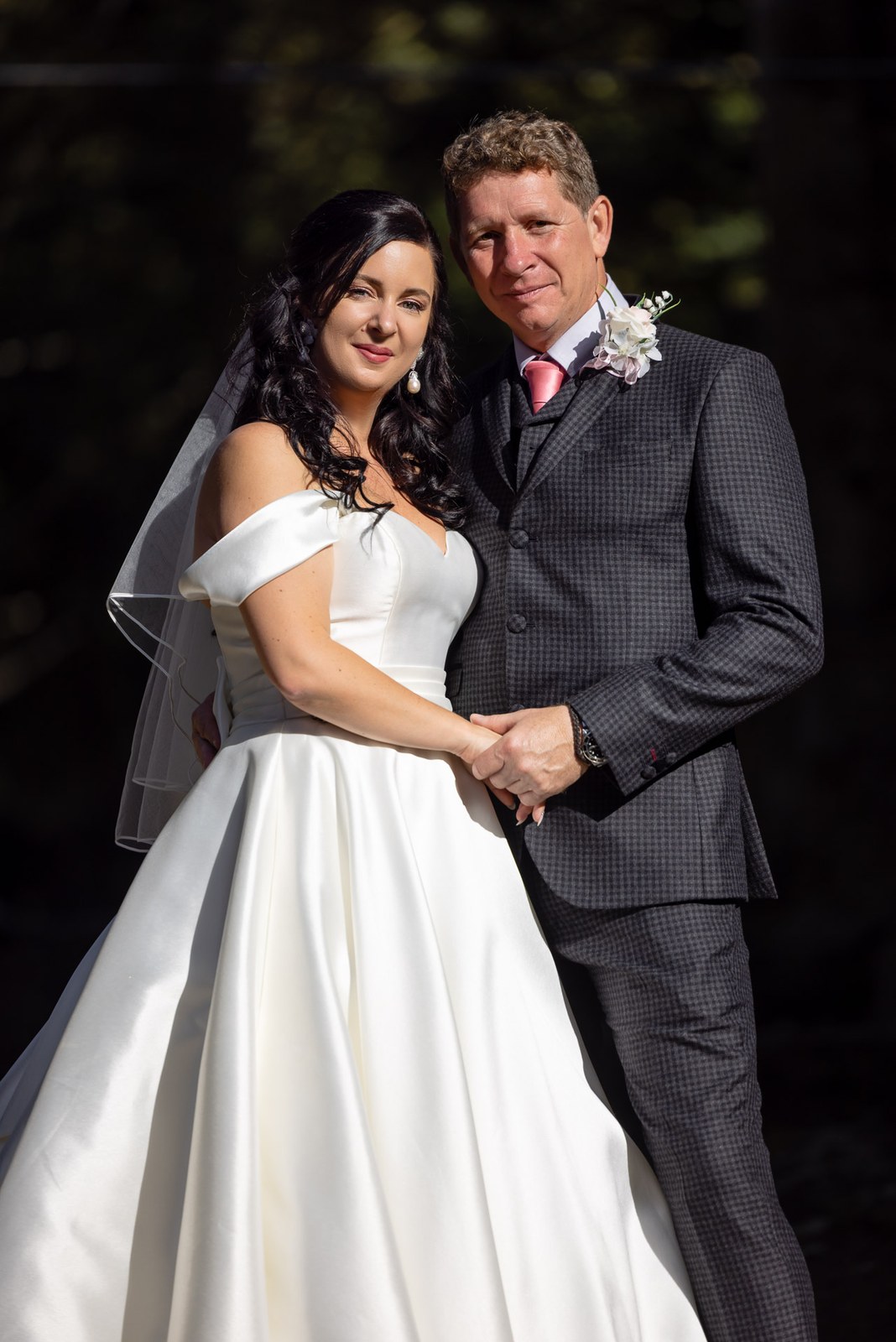 The couple hold each other closely against a shadowed backdrop