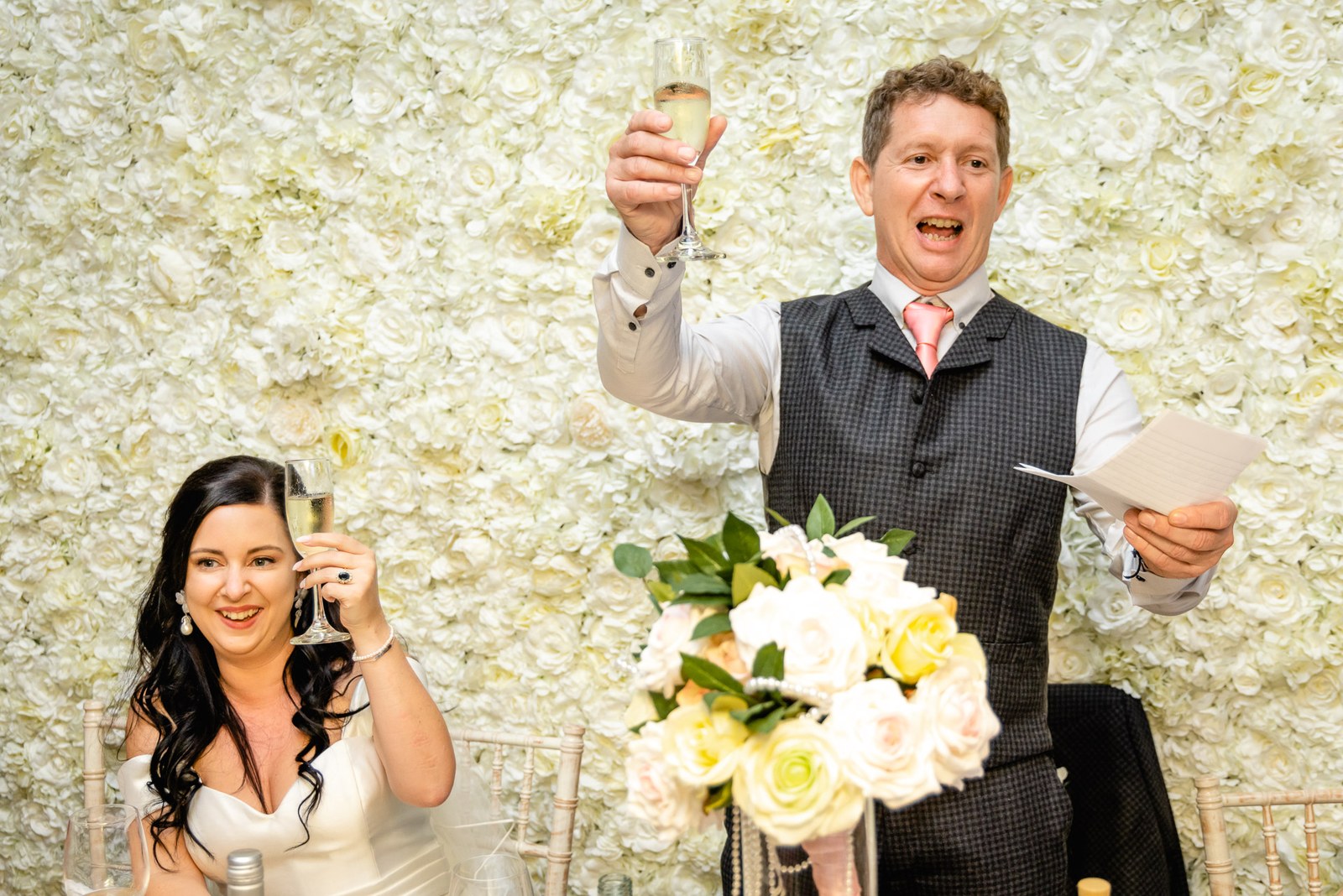 The groom raises his glass in a toast during his speech beside the bride