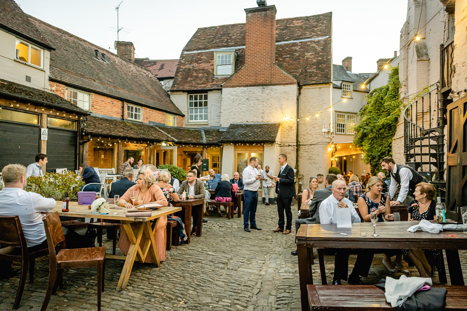 Guests dine at trestle tables in the lamplit cobbled courtyard of the Crown & Thistle