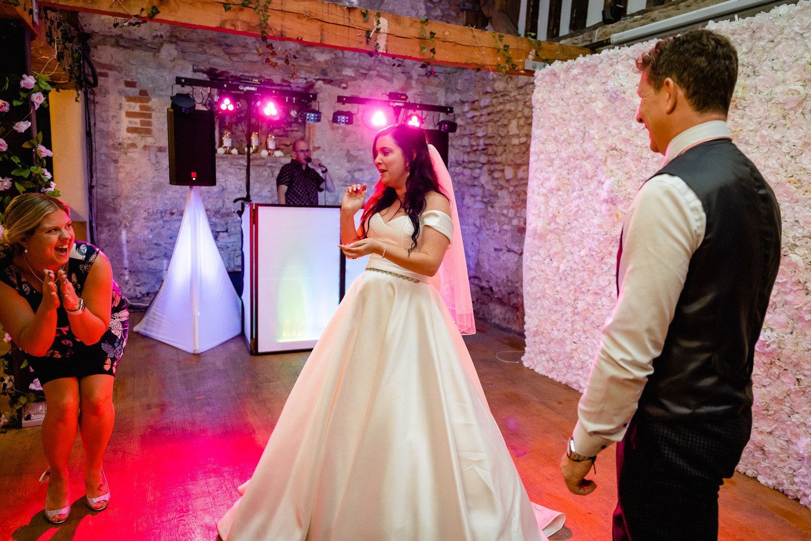 The bride dances in her gown amid pink uplighting against the stone walls