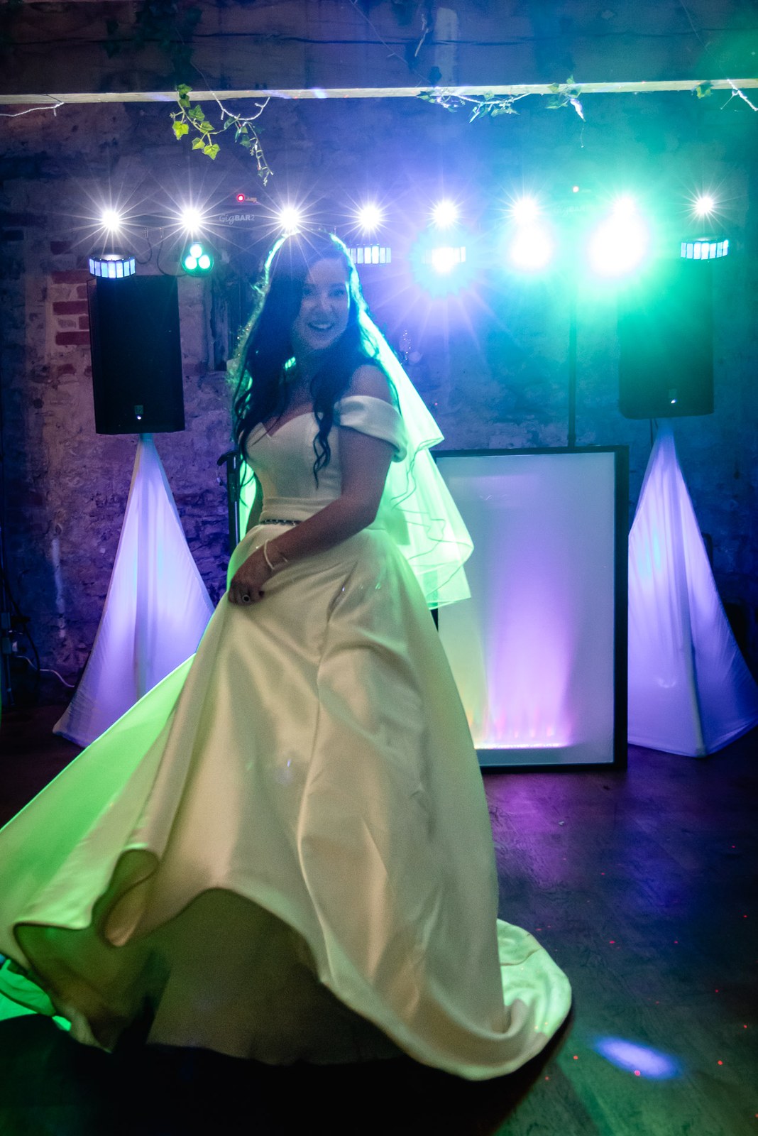 The bride twirls her gown on the dancefloor under coloured disco lights