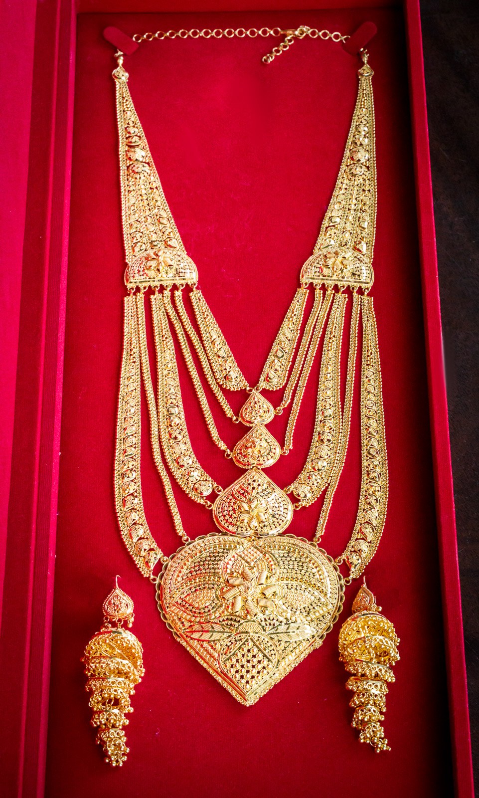 Layered gold bridal necklace displayed on a red velvet box