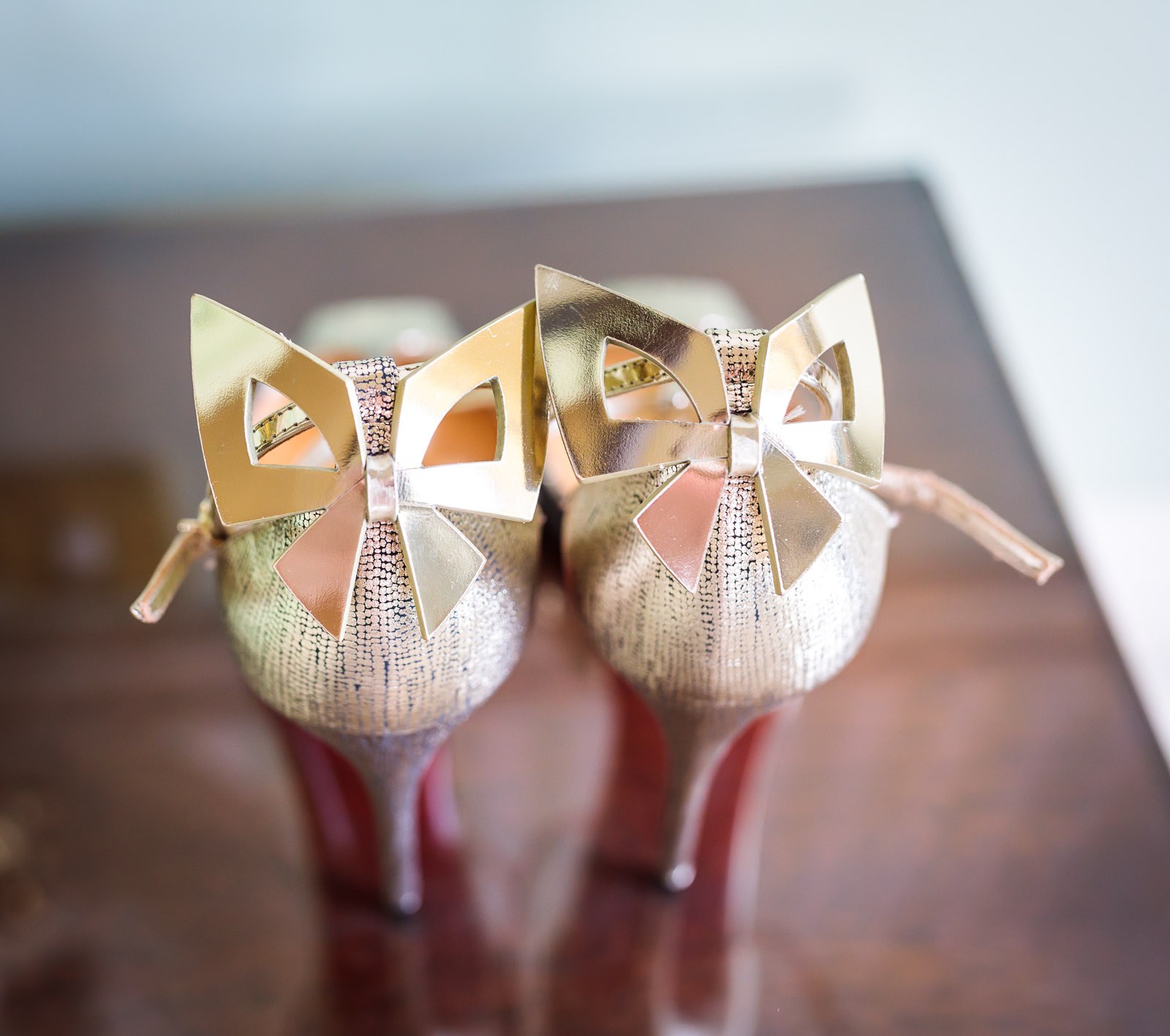 Gold bow-fronted bridal heels standing on a polished table