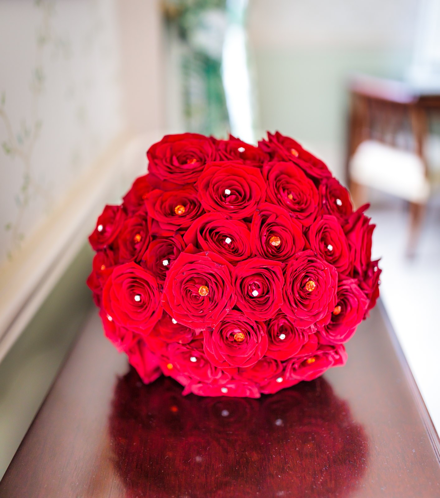 A tight posy of red roses resting on a polished table