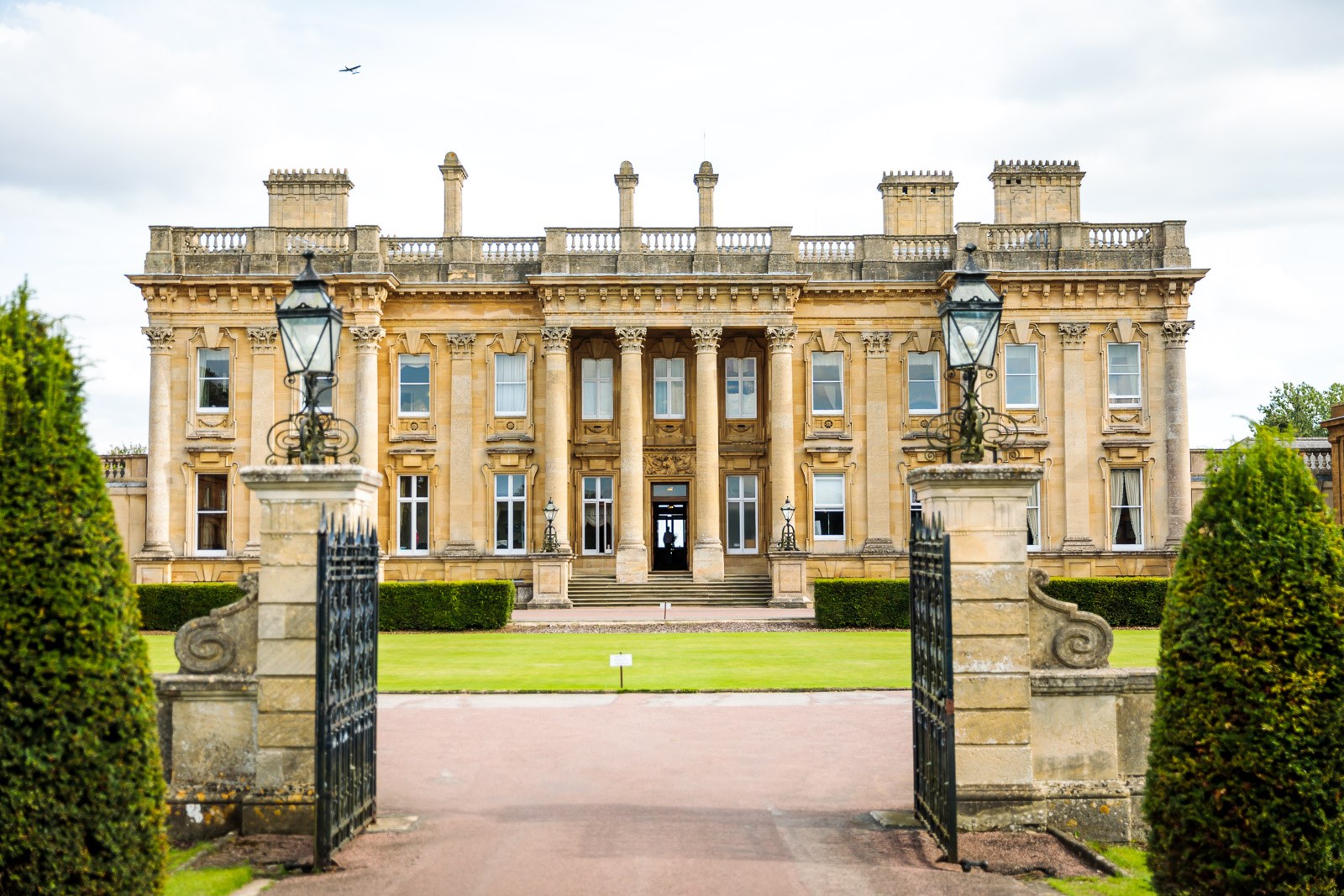 The Palladian facade and columns of Heythrop Park beyond its iron entrance gates