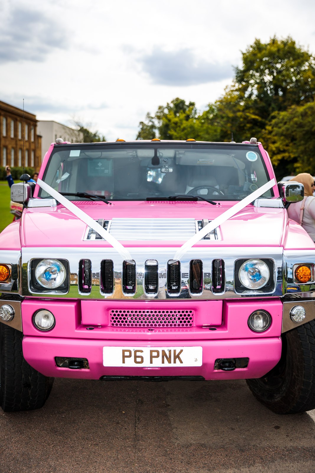 The ribboned front of a pink Hummer limousine on the driveway