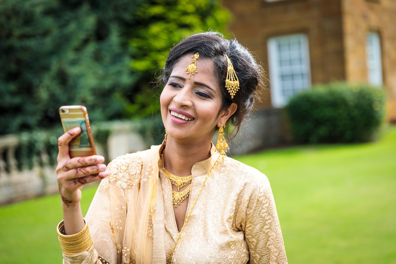A guest in gold takes a selfie on the lawns before Heythrop Park