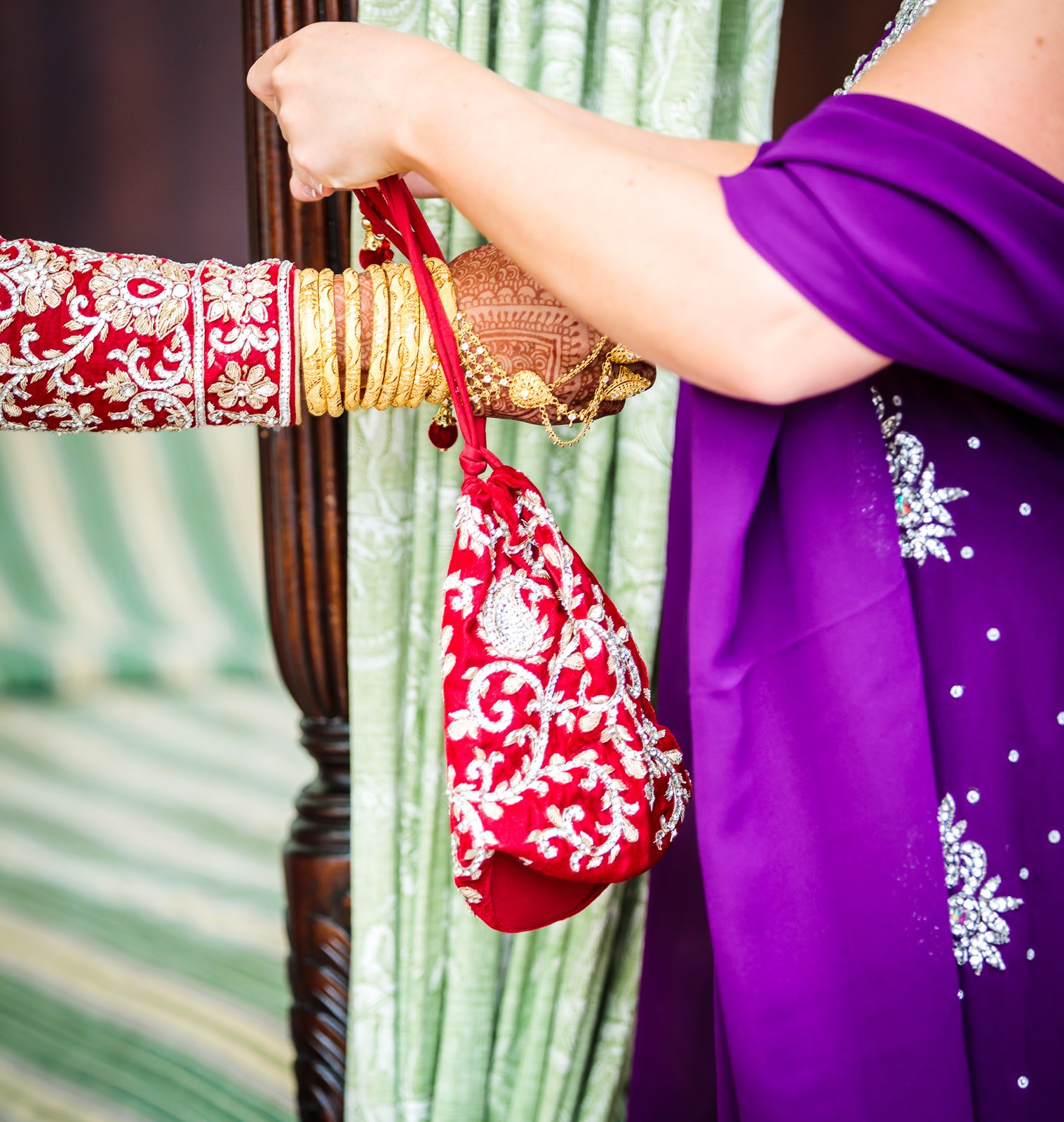 A woman in purple holds out the bride's embroidered red bridal purse