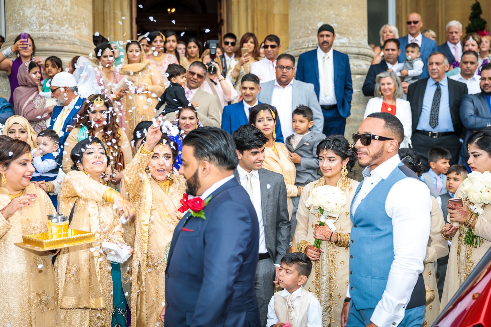 Confetti greets the groom as guests welcome him outside the mansion