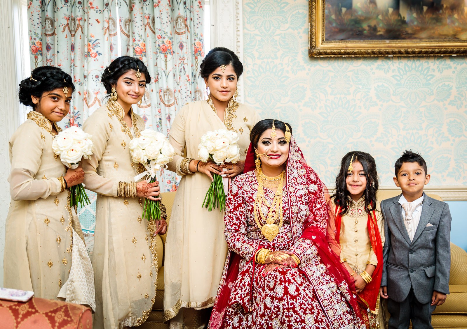 The bride sits with her bridesmaids in cream holding white bouquets