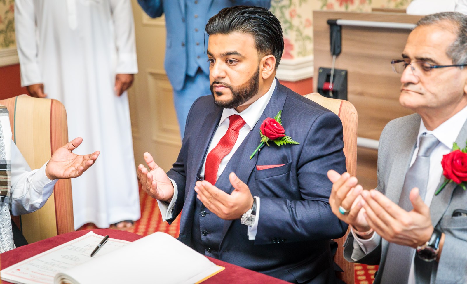 The groom raises his hands in prayer at the nikah table