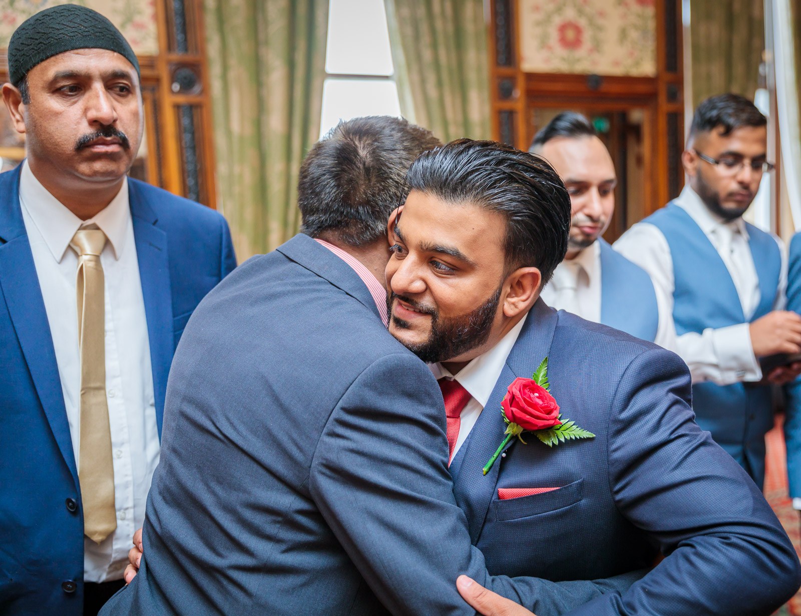 The groom shares an emotional embrace with an older man