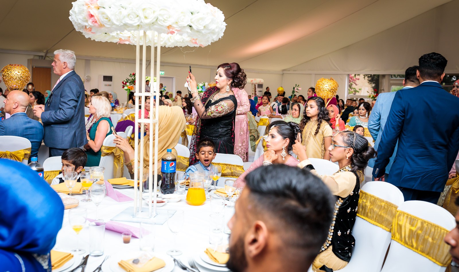 Marquee tables dressed with tall floral centrepieces as guests mingle
