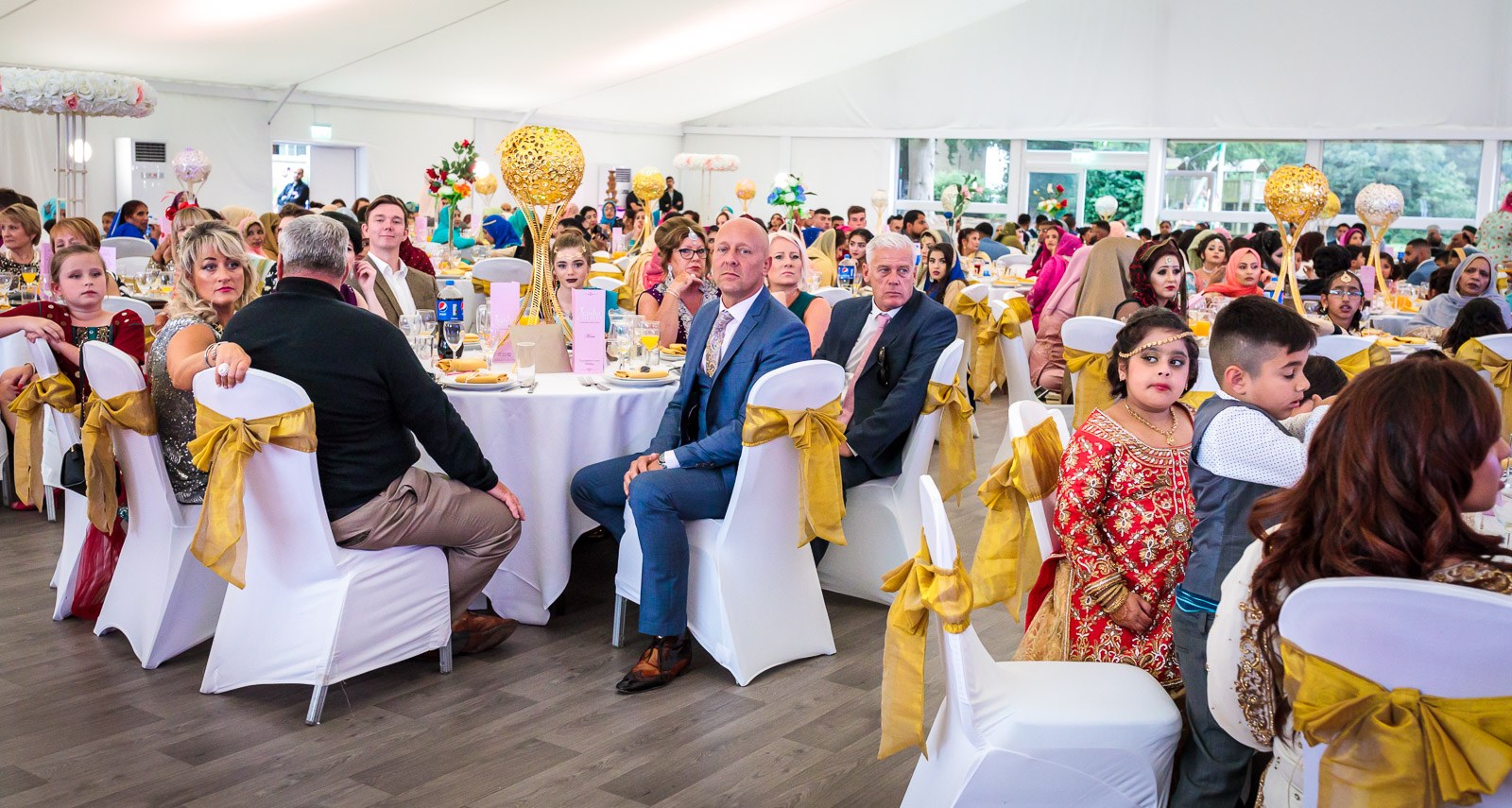 Guests seated among tall gold centrepieces at the reception