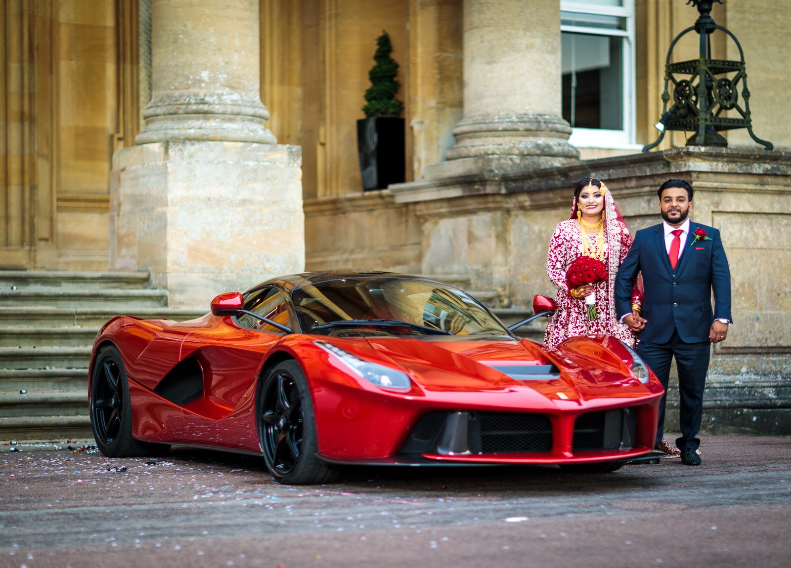 The couple stand with the red Ferrari before the portico of Heythrop Park