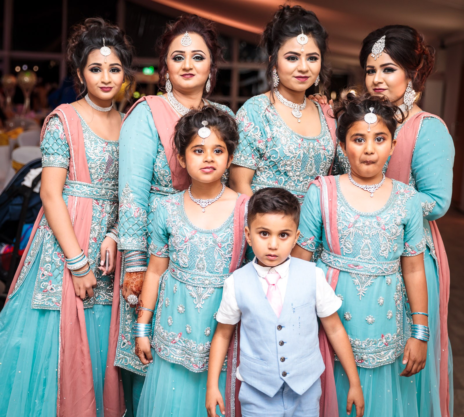 Women and children in matching aqua and pink outfits pose together