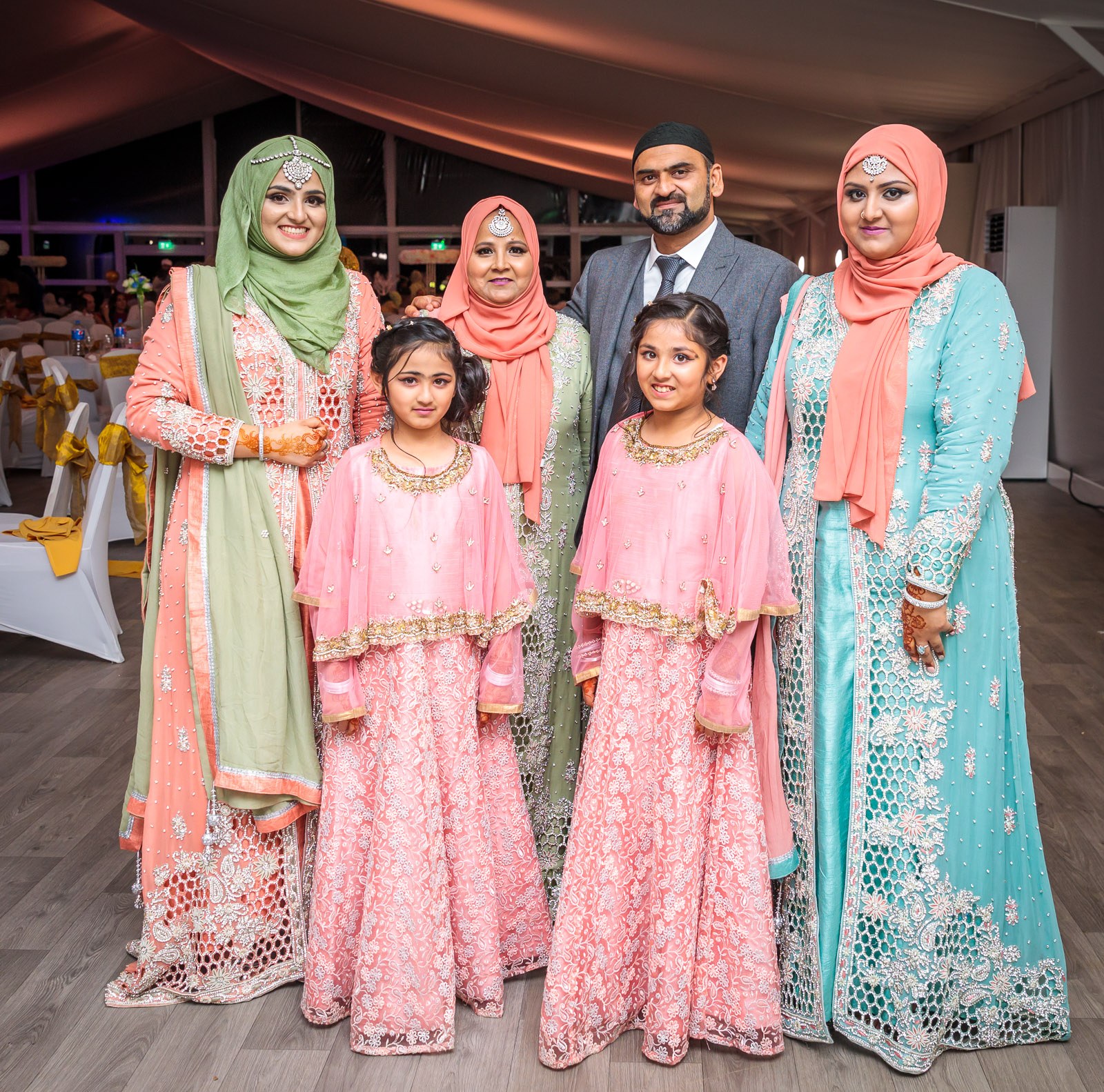 Women and girls in pink and mint gather in the marquee