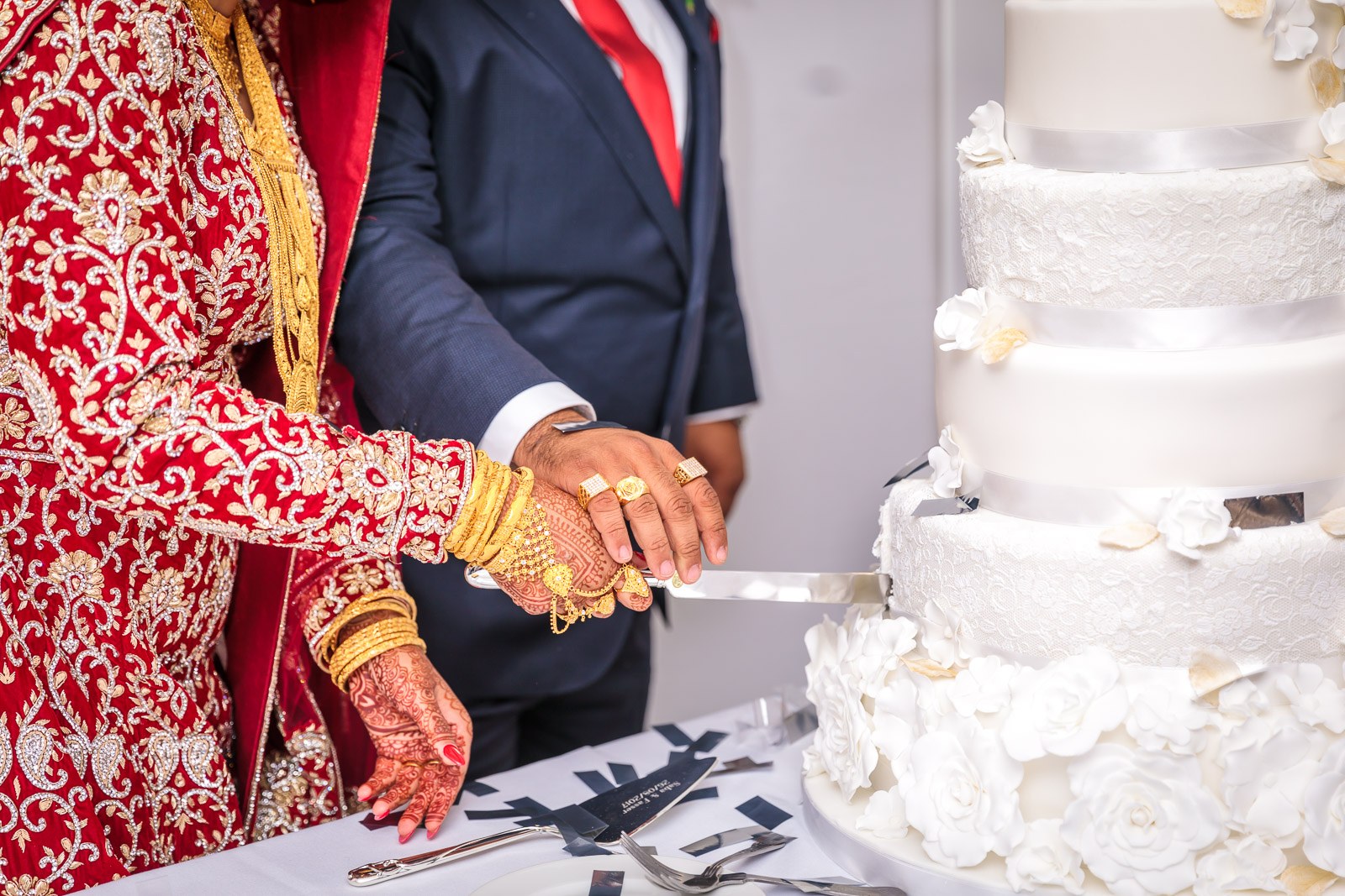 Close-up of the couple's hands cutting the tiered white cake