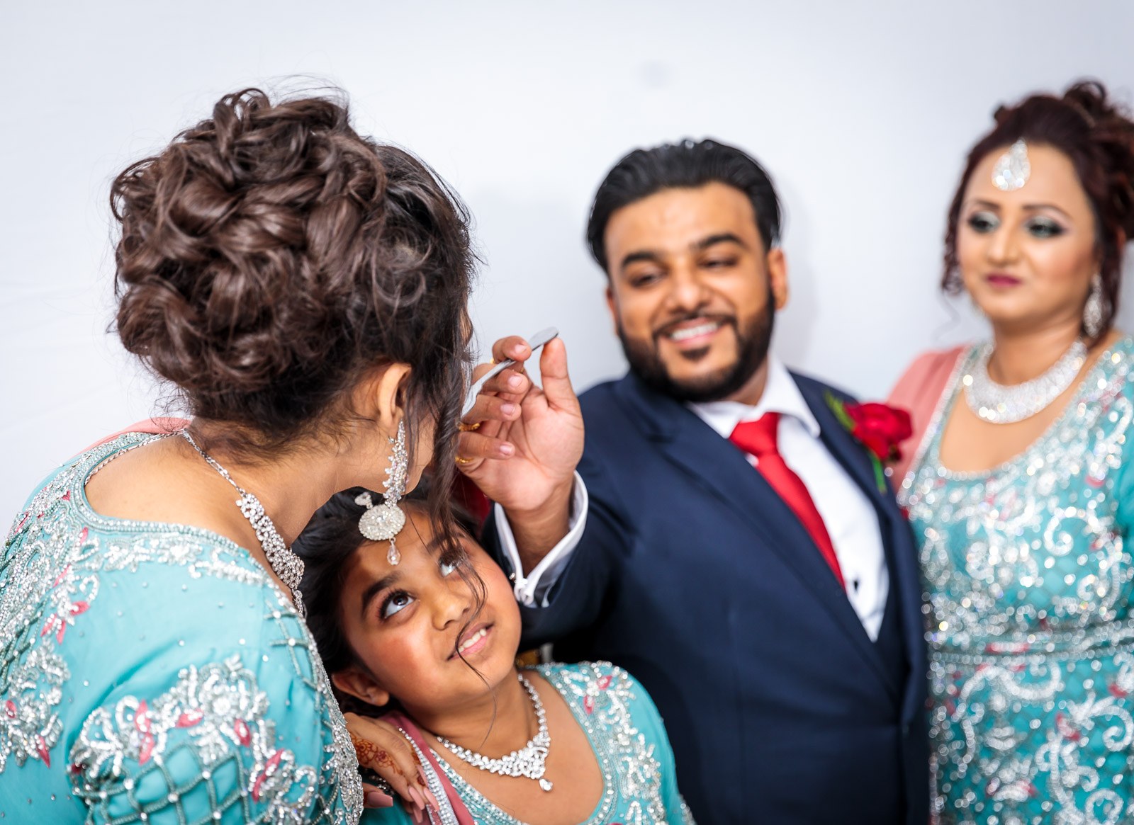 Guests in aqua share cake with a young girl as the groom looks on