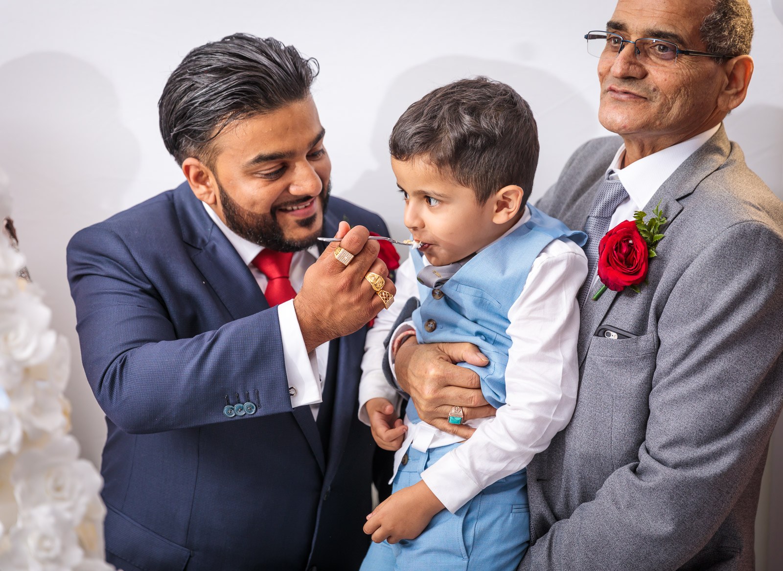 The groom offers cake to a small boy held by an elder