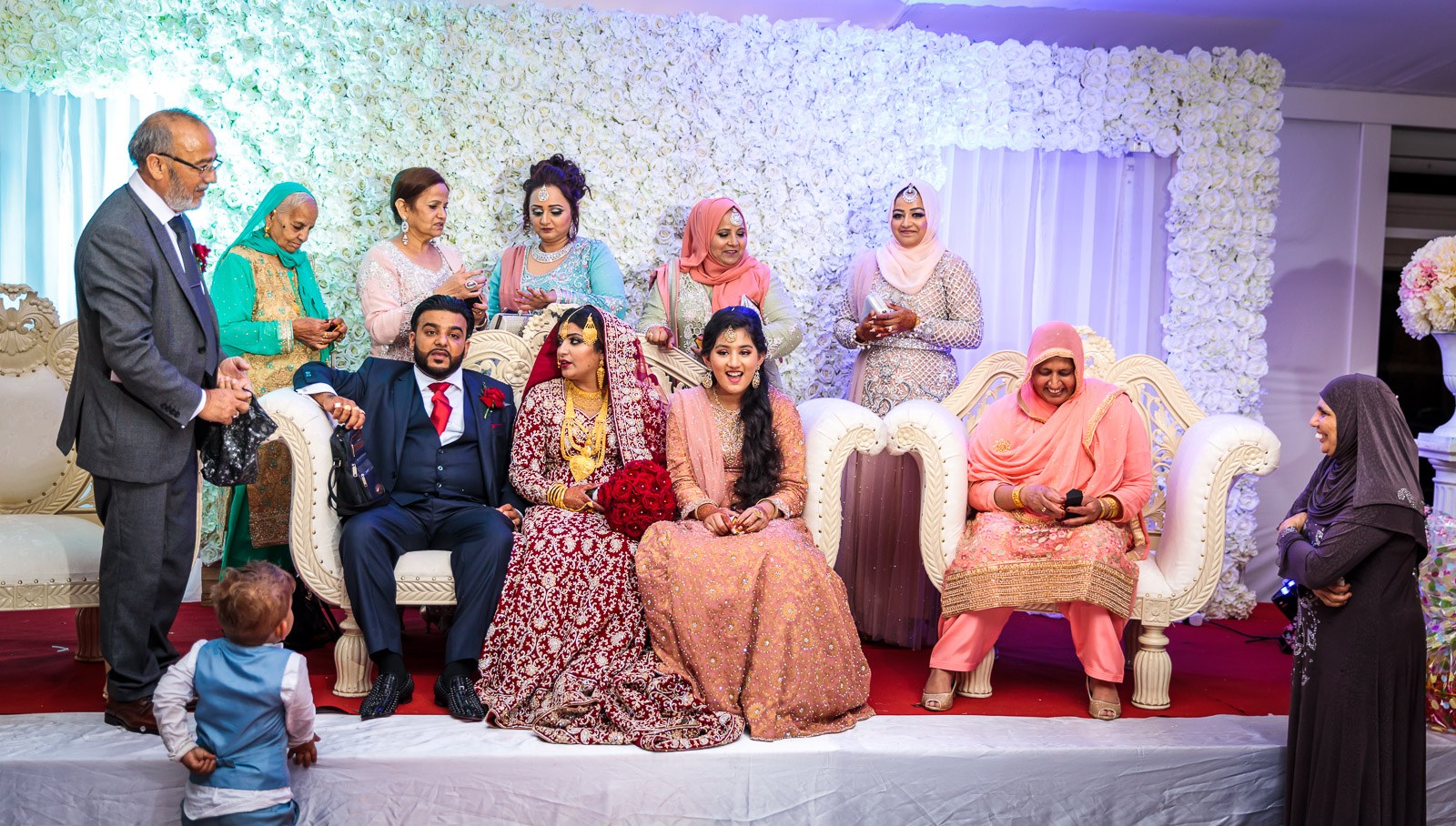 The family gathers on the stage sofa before the white flower wall