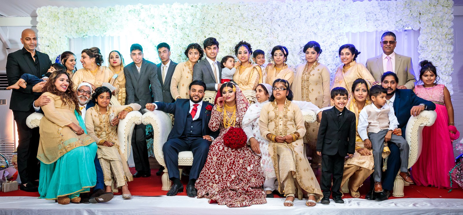 A large family group portrait on the flower-wall stage