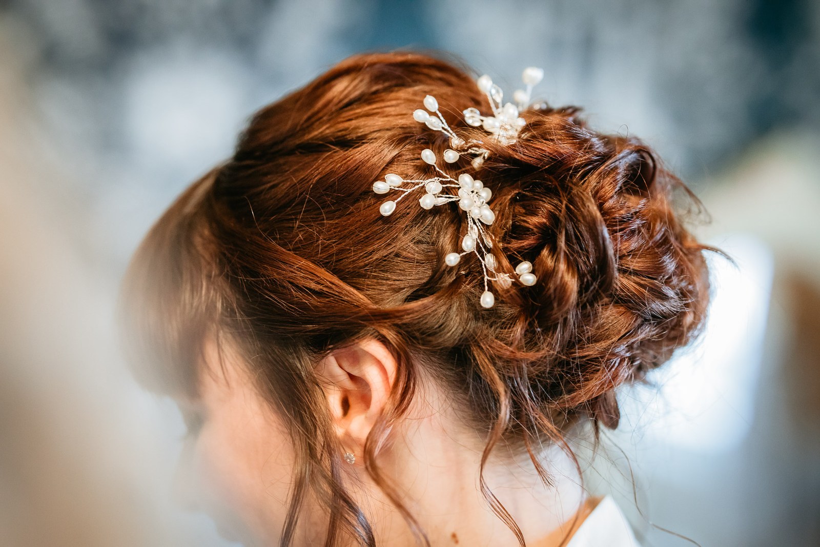 Close-up of the bride's auburn updo pinned with a pearl hair vine