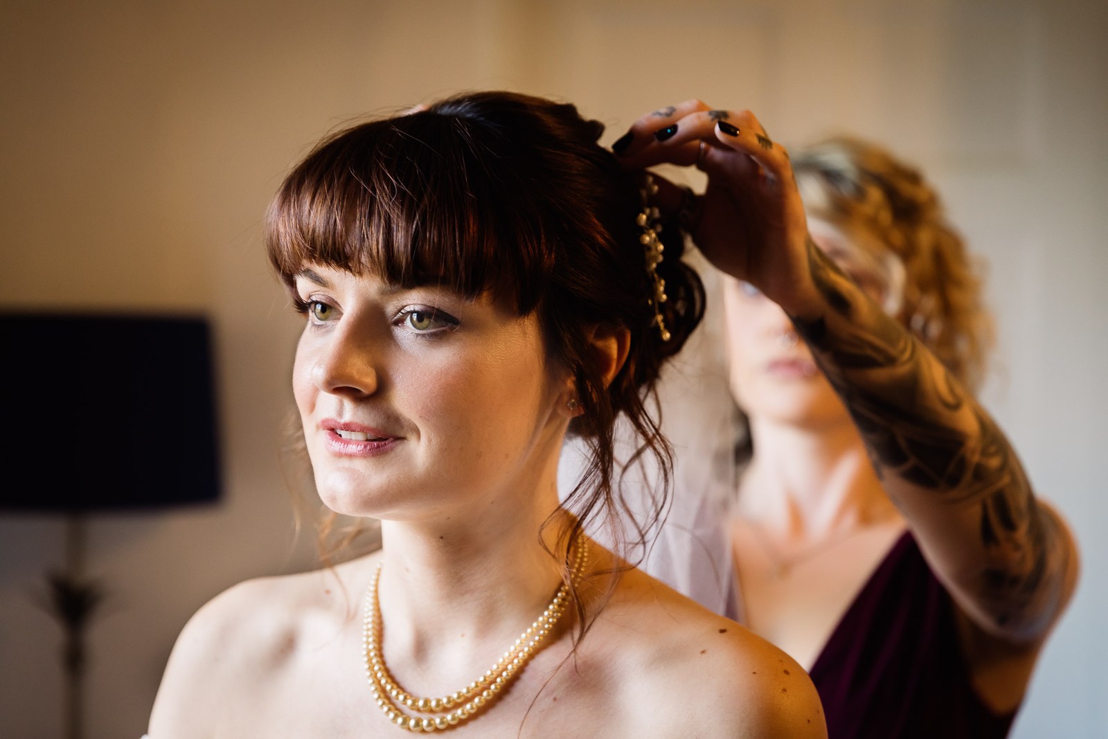Close-up of the bride's face as her hair is finished, wearing pearls