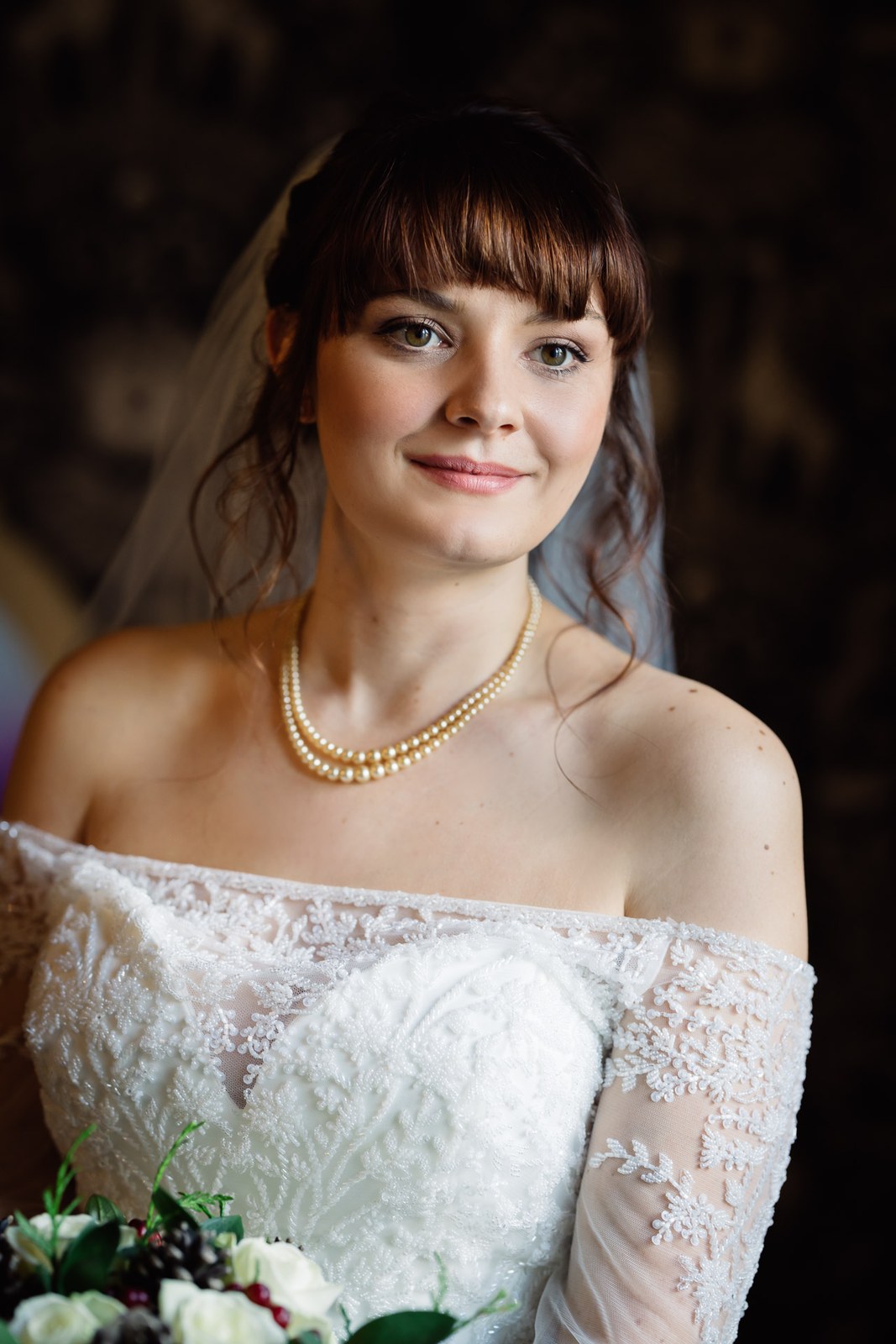 Portrait of the bride in her veil and pearls holding her bouquet