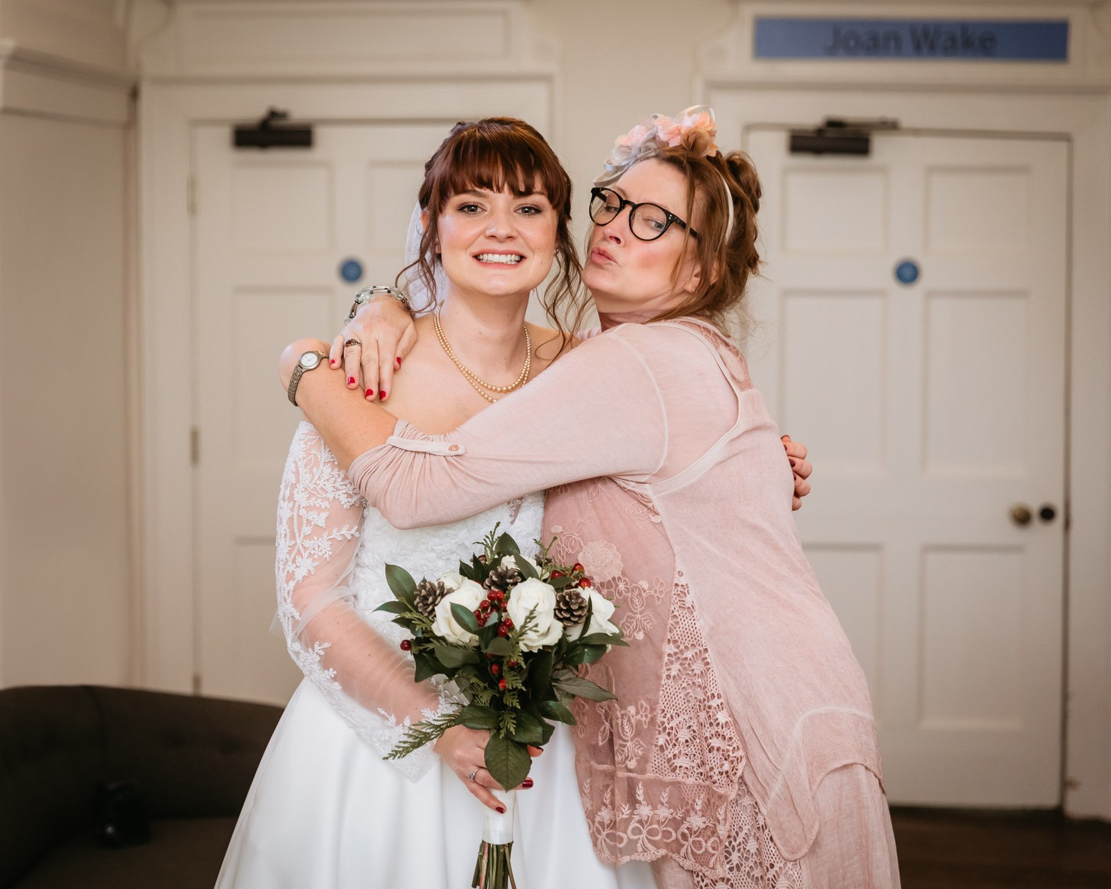 A woman in pink hugs the bride warmly before the ceremony