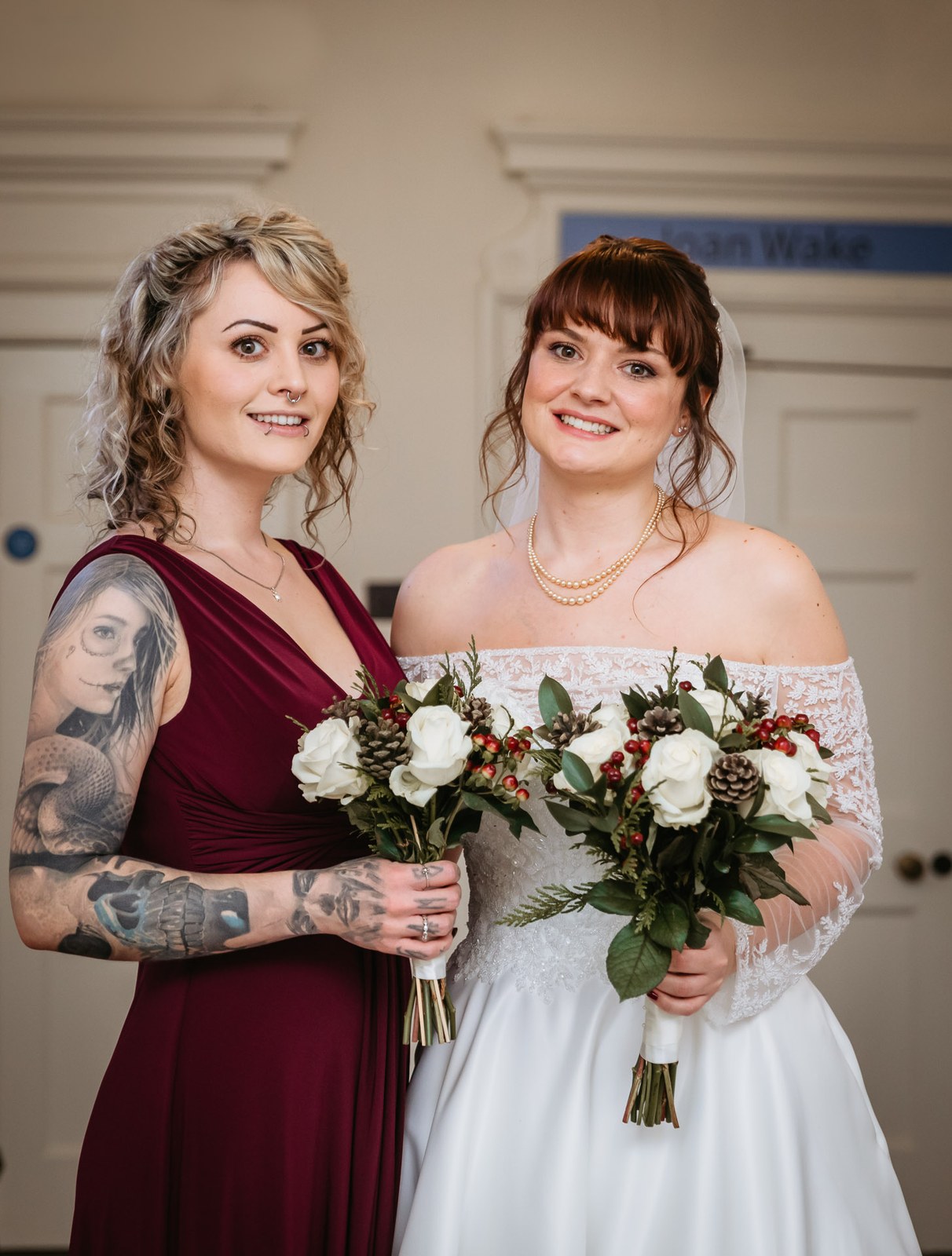 The bride and her bridesmaid in burgundy hold their winter bouquets