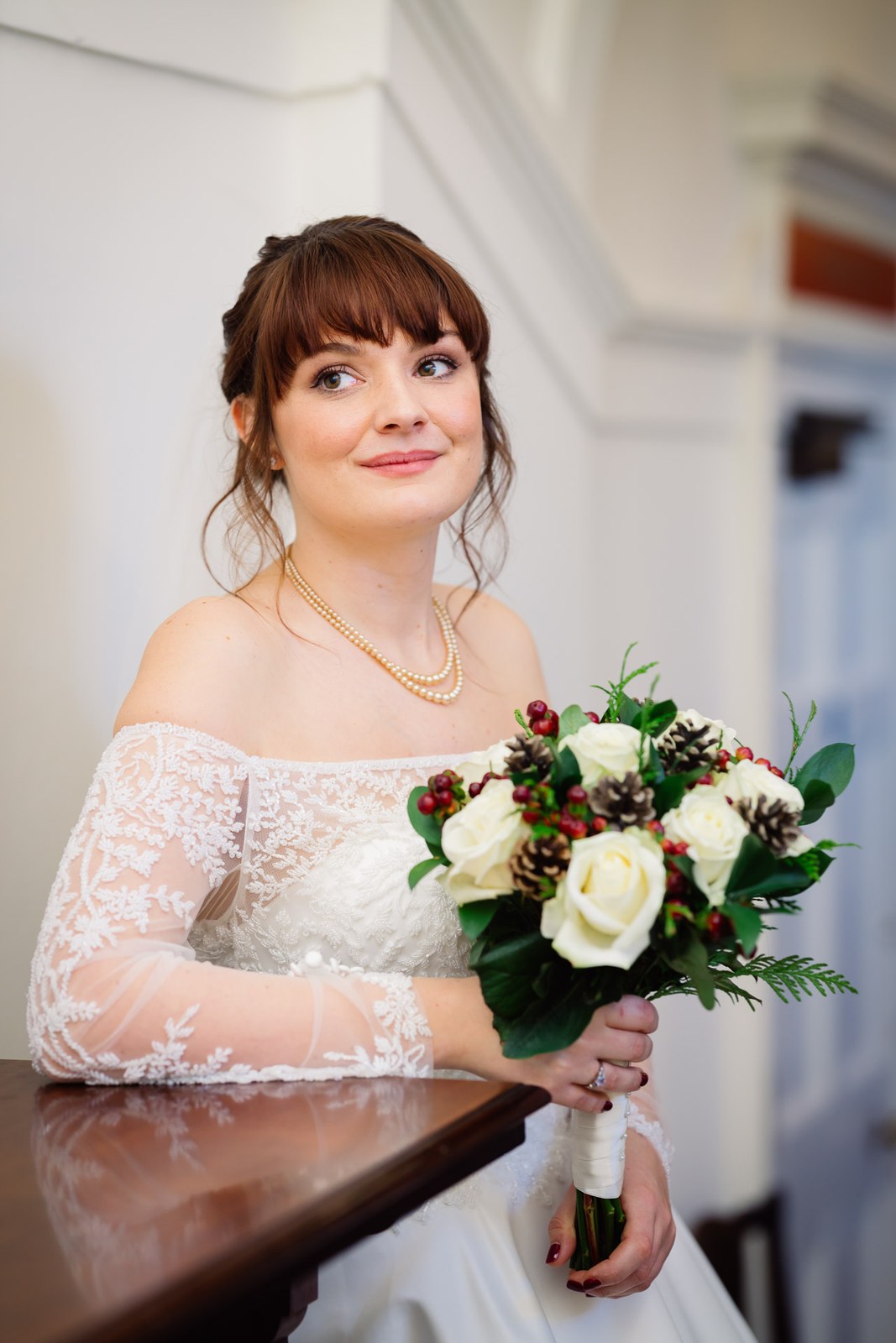 The bride leans on a wooden rail with her bouquet, smiling