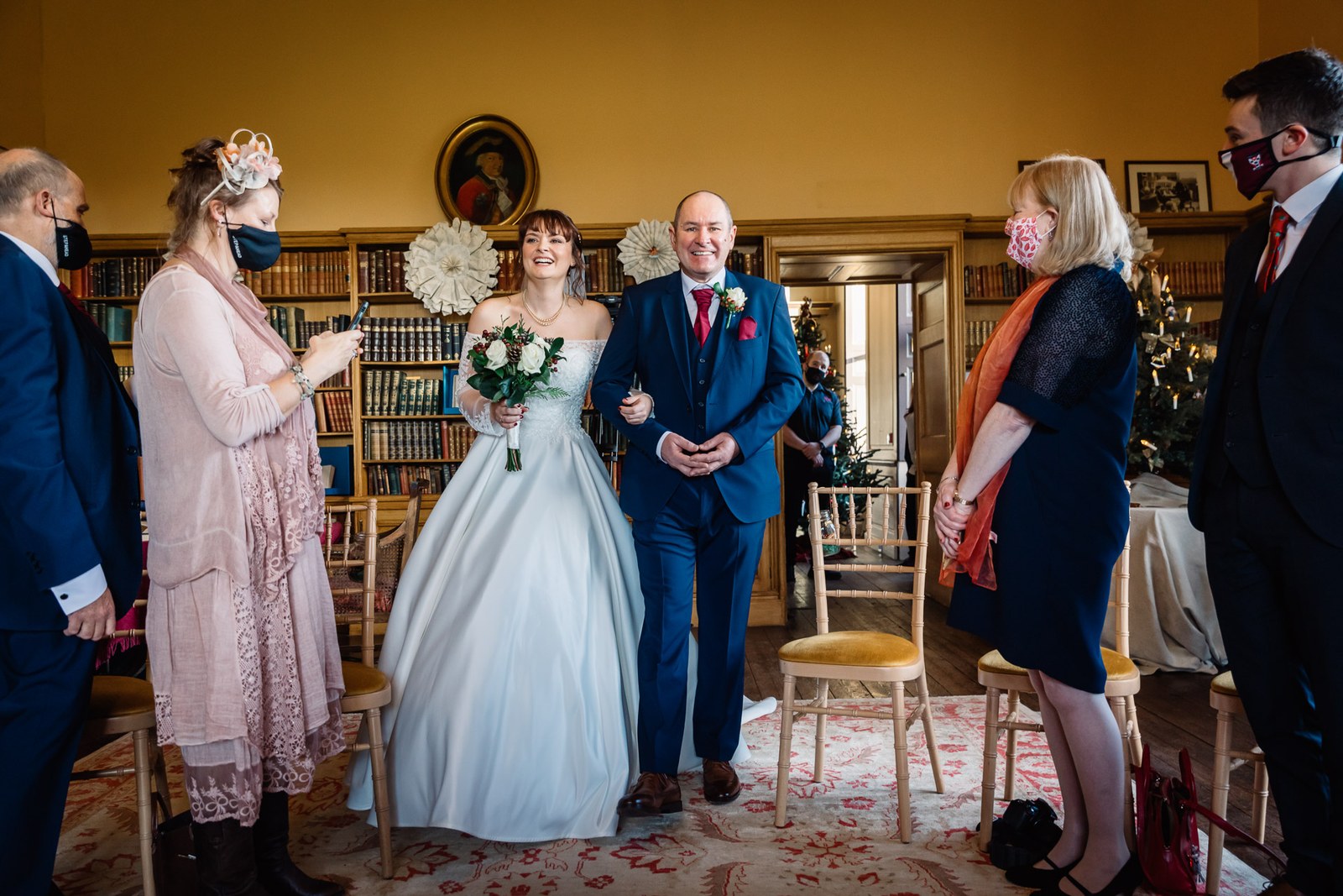 The bride and her father walk in as standing guests look on
