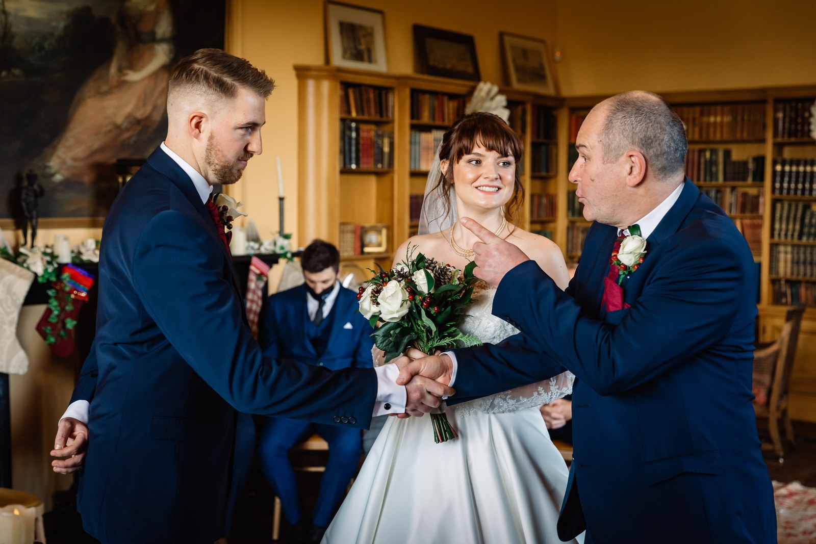The groom takes the bride's hand from her father at the ceremony