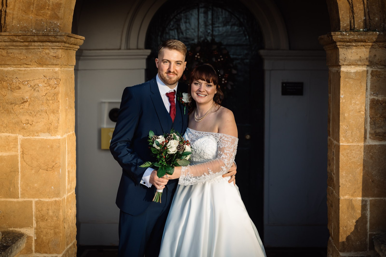 The couple embrace under the arched stone doorway of Delapre Abbey