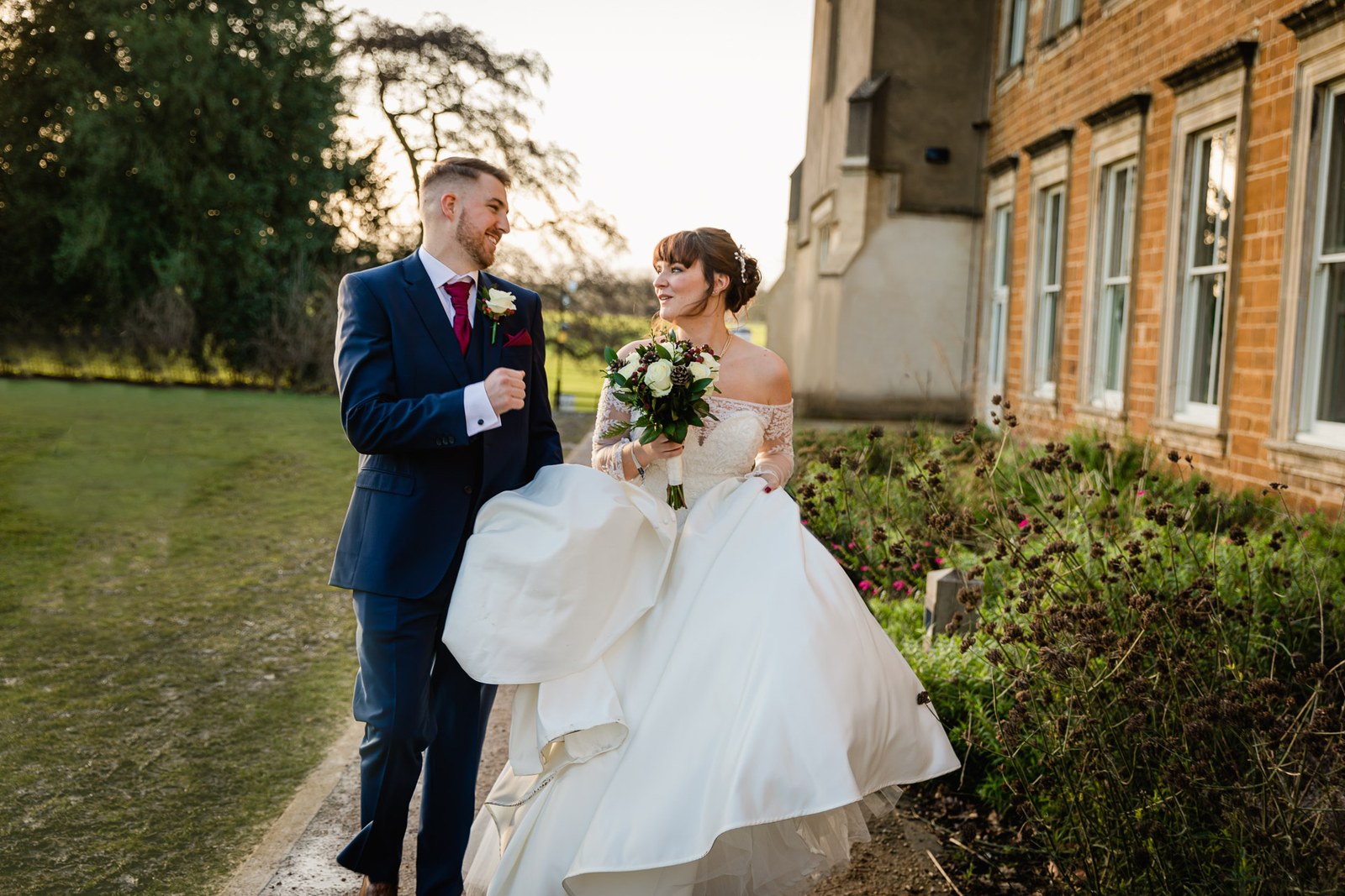 The couple walk a path beside the red-brick range at Delapre Abbey