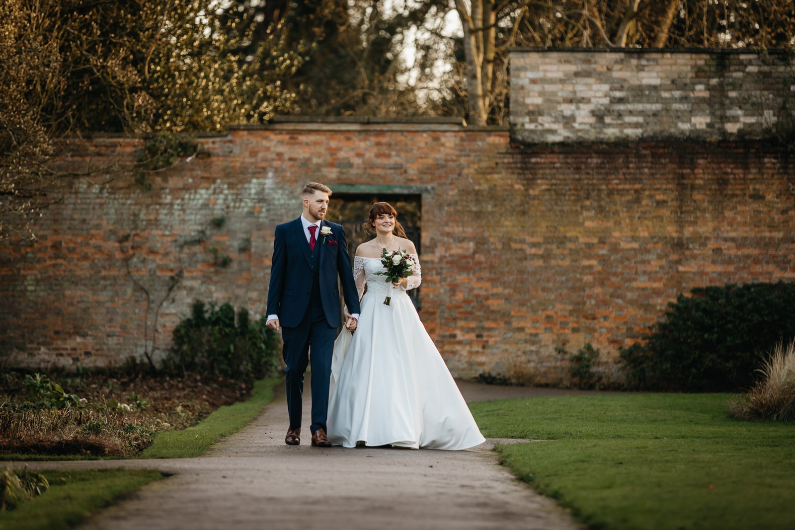 The couple stroll a path through the walled garden at Delapre Abbey