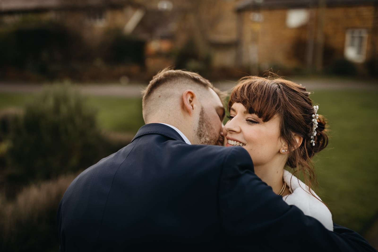 The groom nuzzles the laughing bride's cheek in the winter garden