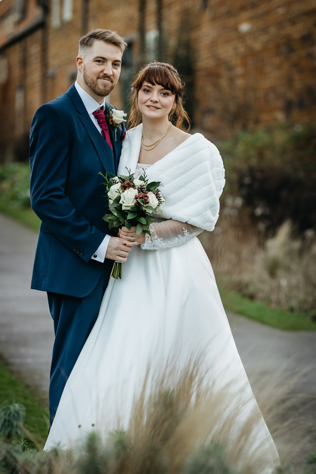 Portrait of the couple on a garden path, the bride holding her bouquet