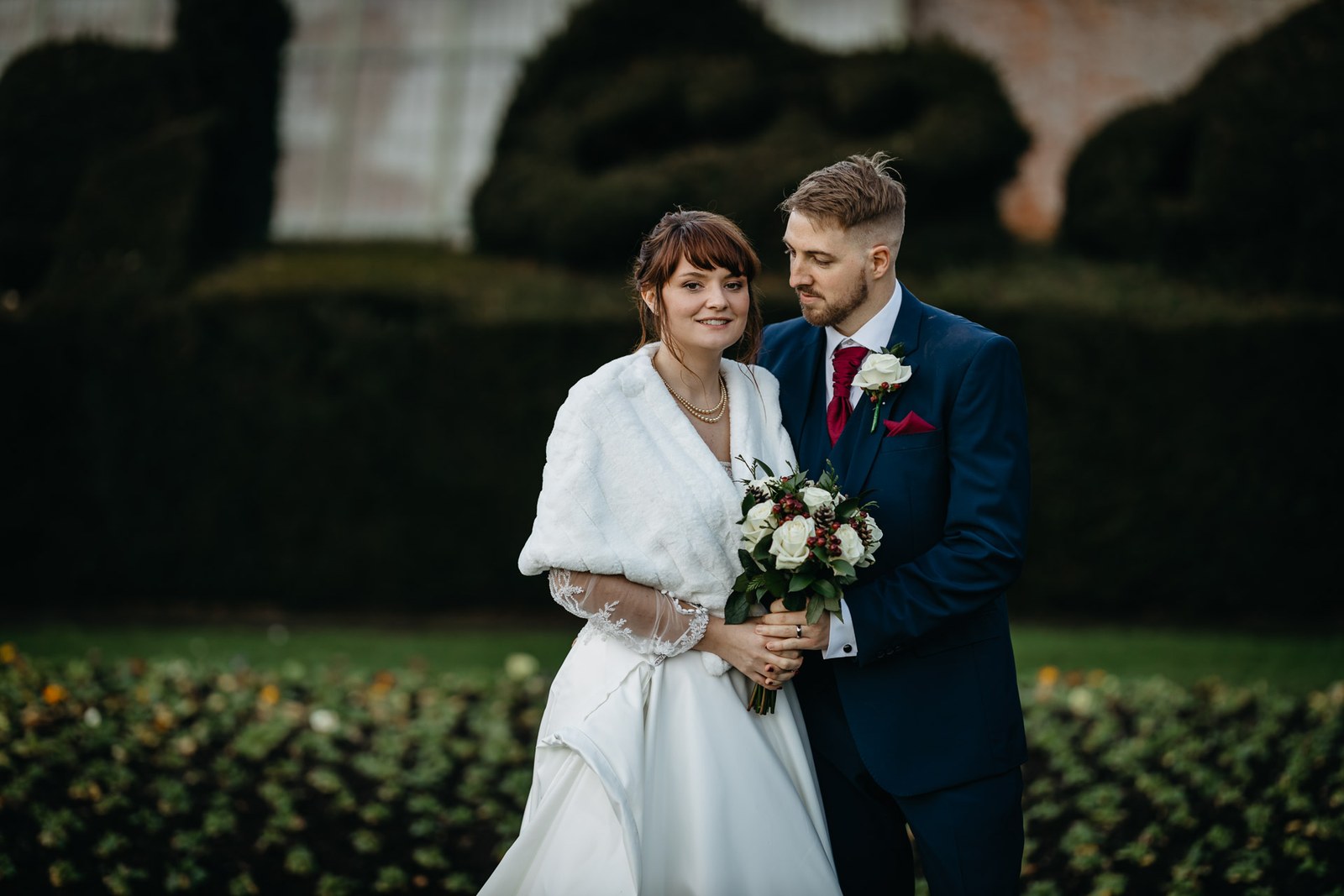 The couple stand among the dark clipped yews in the gardens of Delapre Abbey