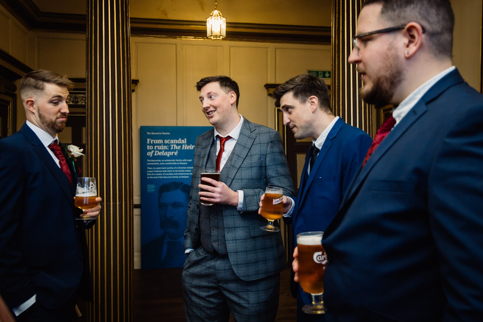 The groom and guests share a drink by a doorway in Delapre Abbey