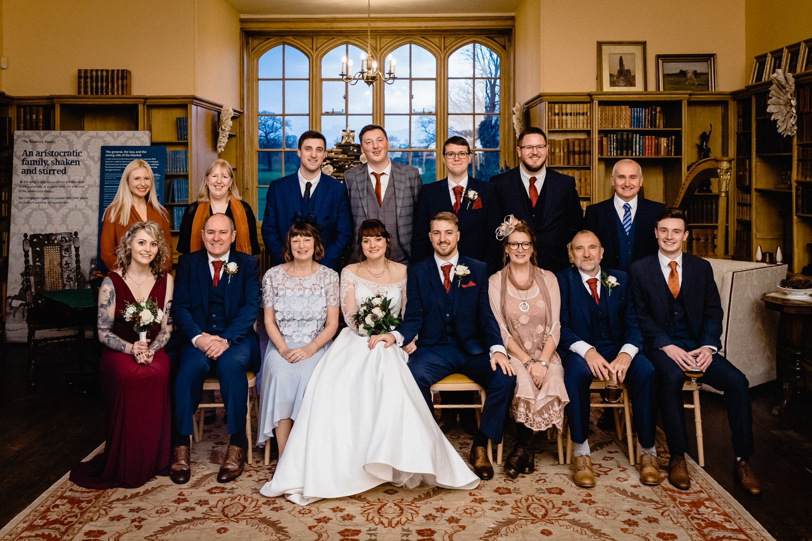A large group portrait seated in the book-lined library at Delapre Abbey