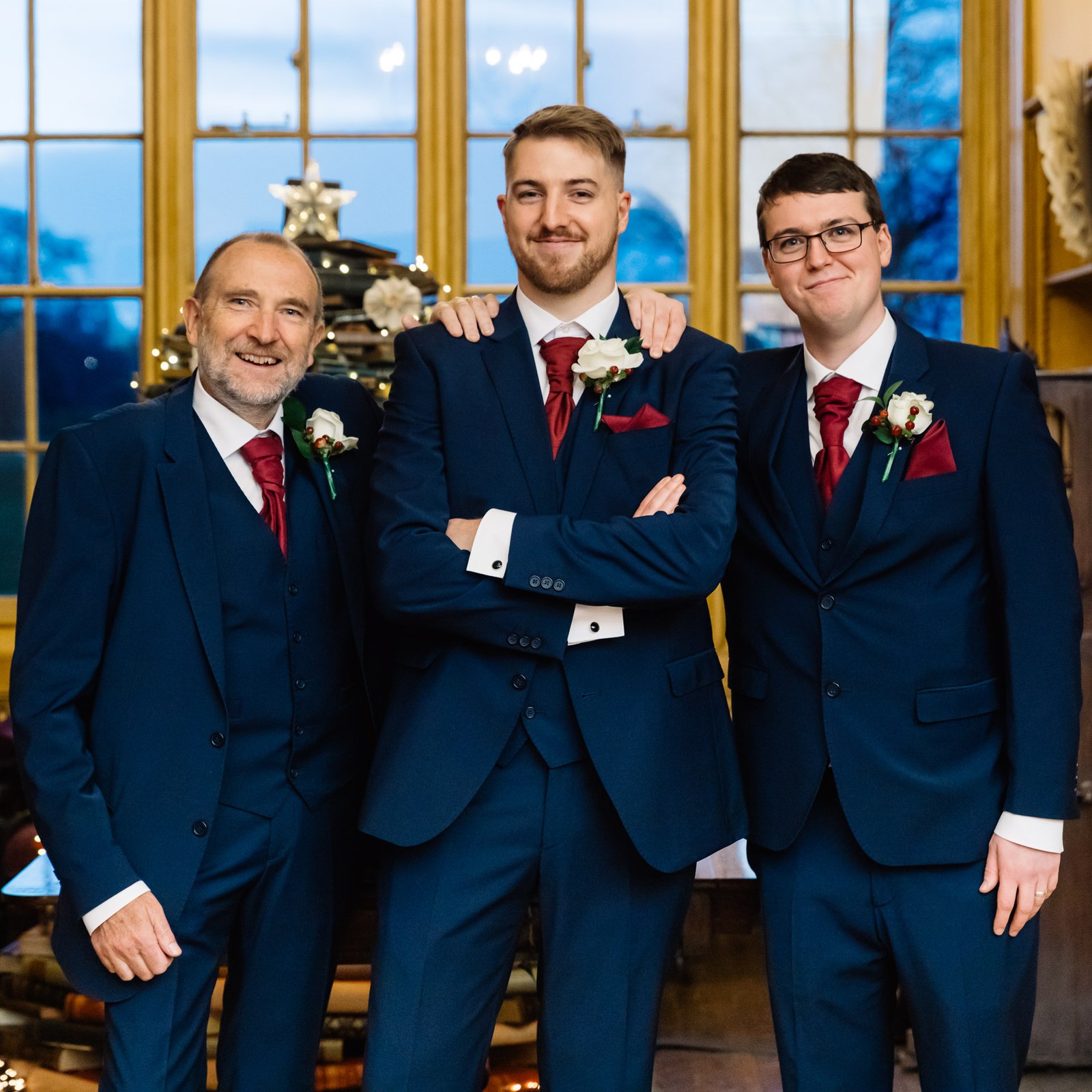 The groom poses with two of the wedding party in the library at Delapre Abbey