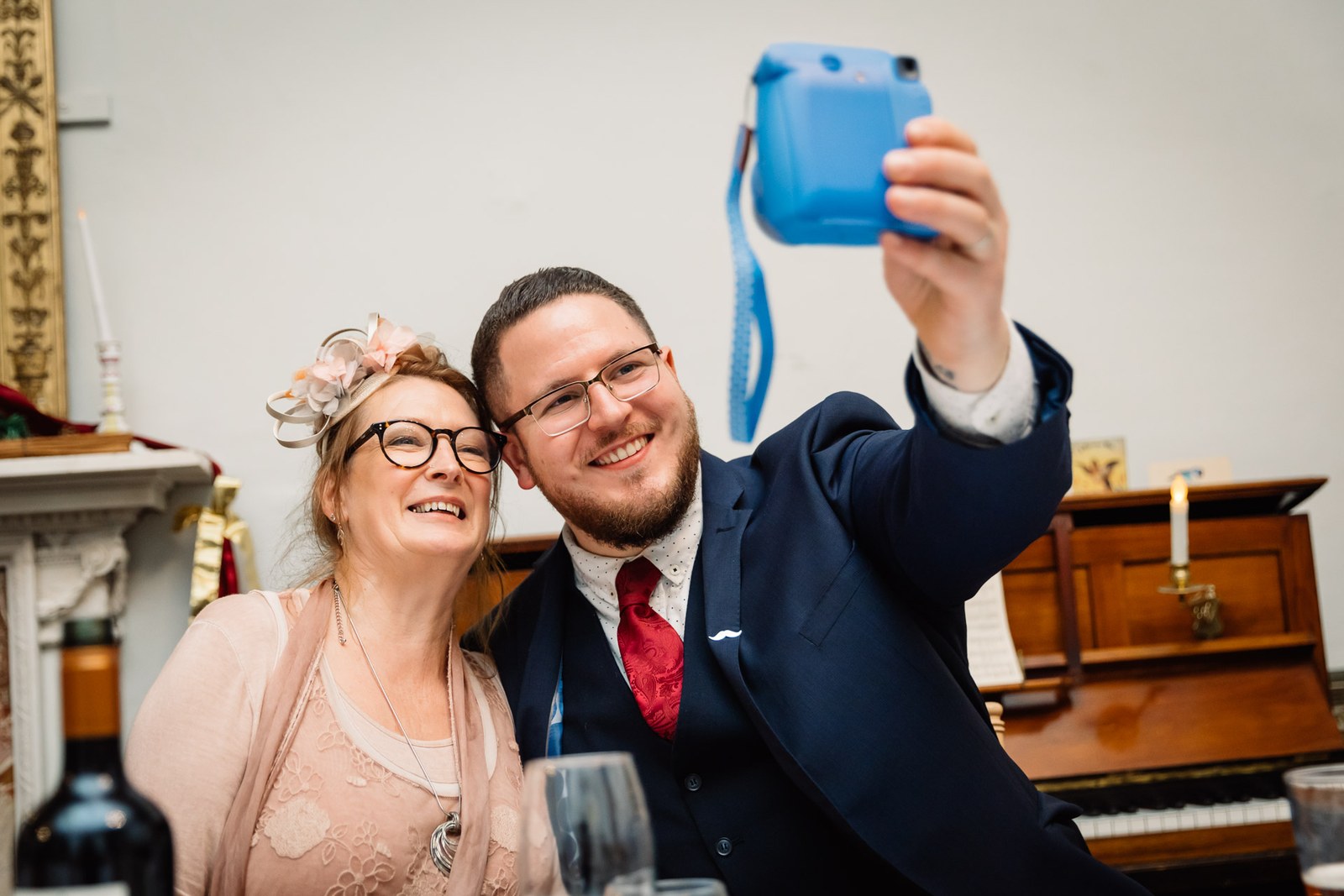 Two guests pose for an instant-camera selfie at the reception table