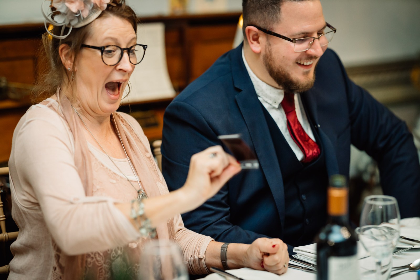 A guest gasps in surprise at the reception table as the man beside her laughs