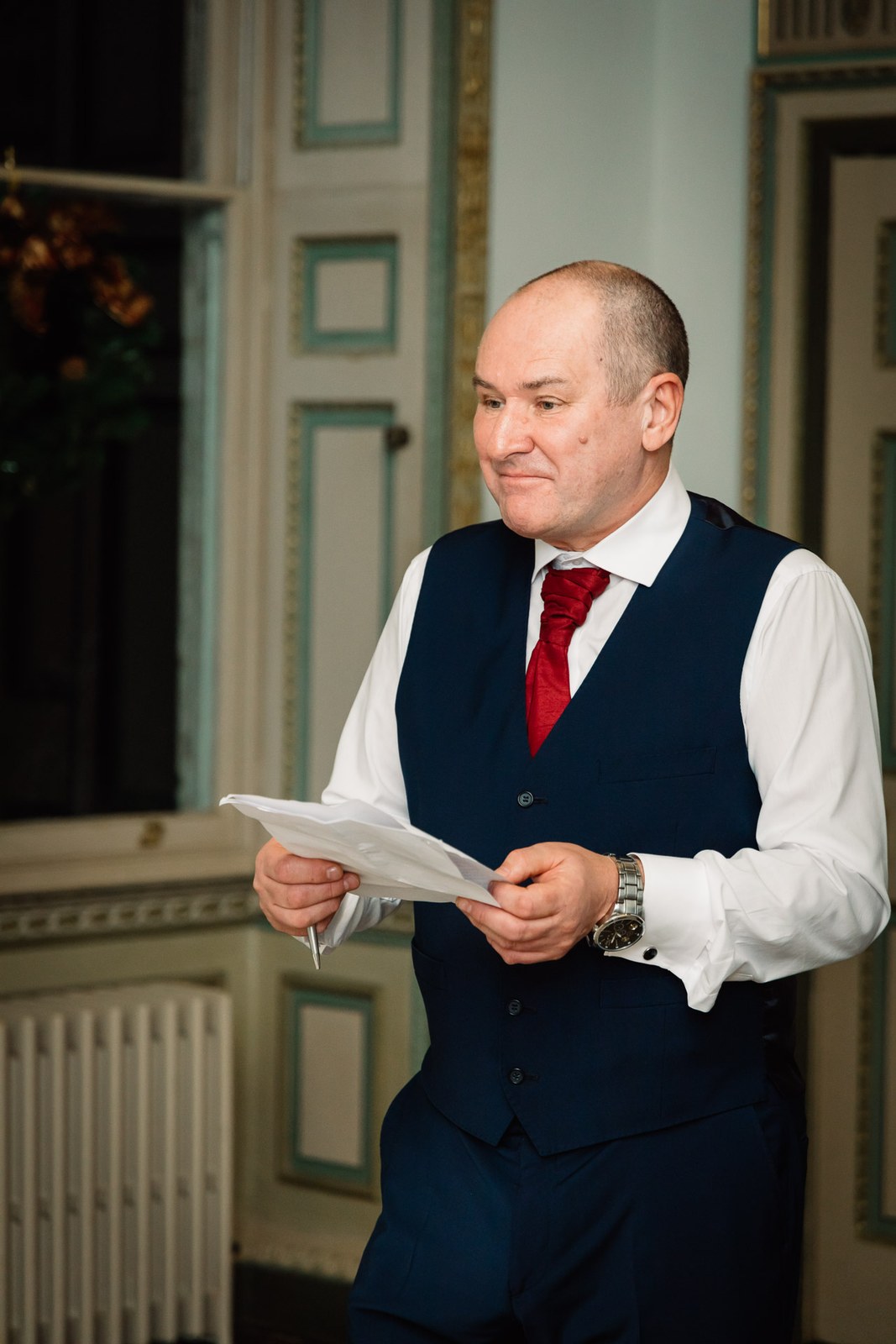 An older man in a navy waistcoat reads his speech