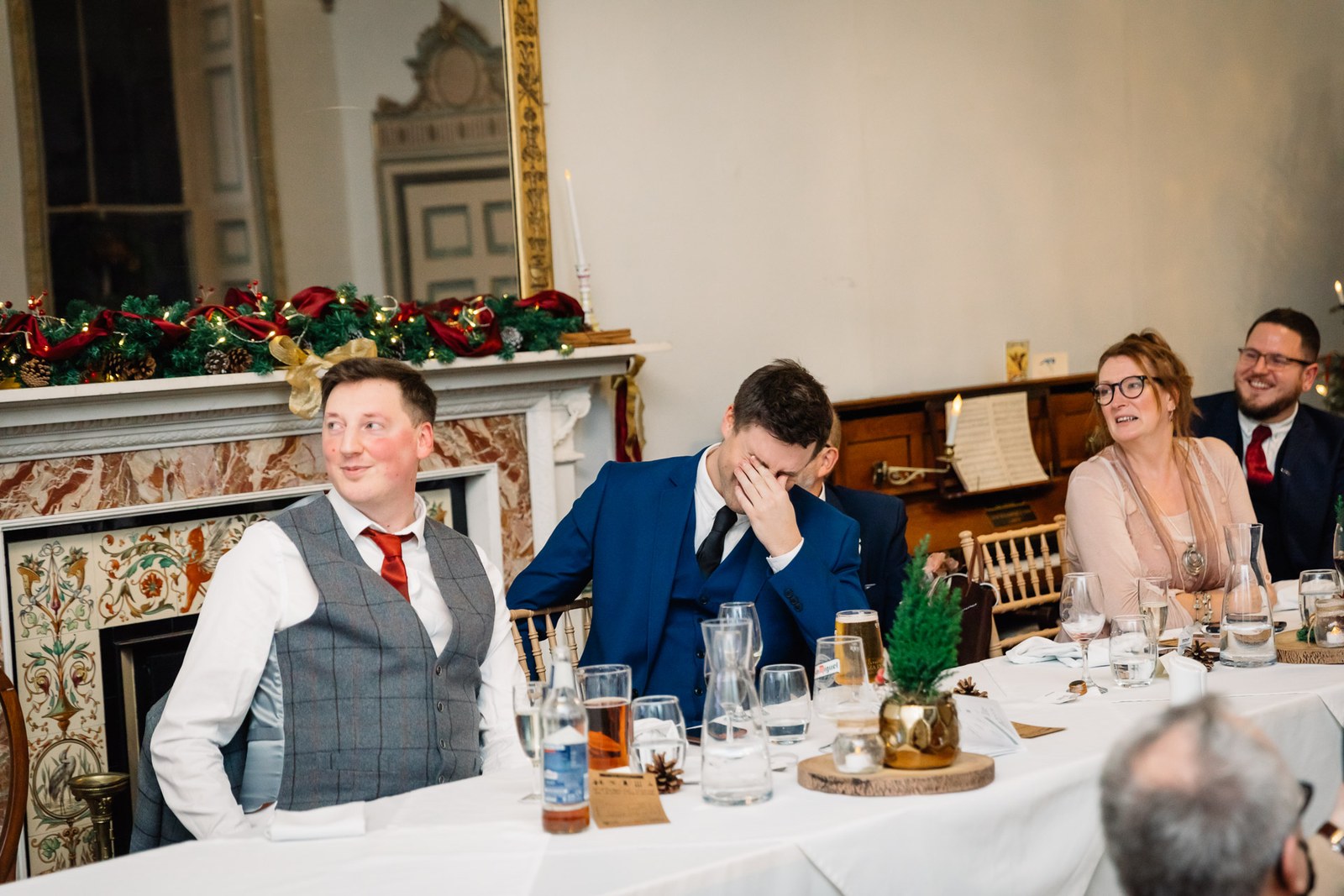 Guests watch the speeches, one covering his face with laughter
