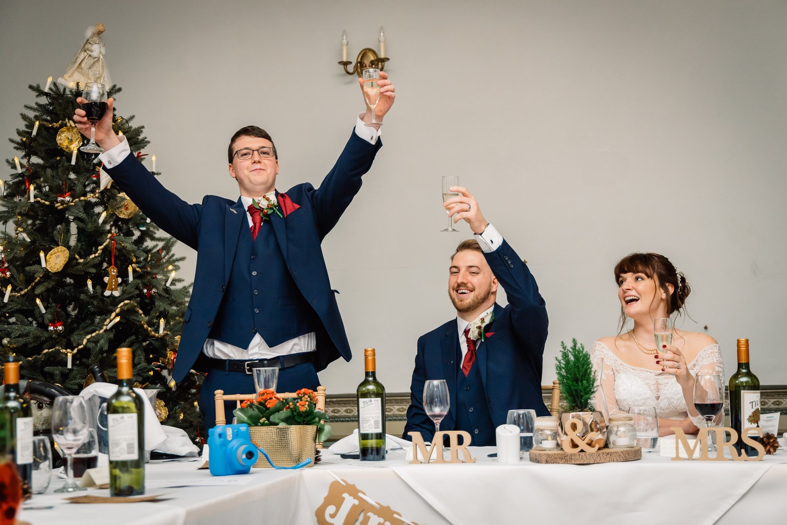 A speaker throws his arms up in a toast beside the seated couple